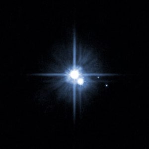 In 2005, this image from NASA's Hubble Space Telescope was used to identify two new moons orbiting Pluto. Pluto is in the center. The moon Charon is just below it. The newly discovered moons, Nix and Hydra, are to the right of Pluto and Charon. Credits: NASA, ESA, H. Weaver (JHU/APL), A. Stern (SwRI), and the HST